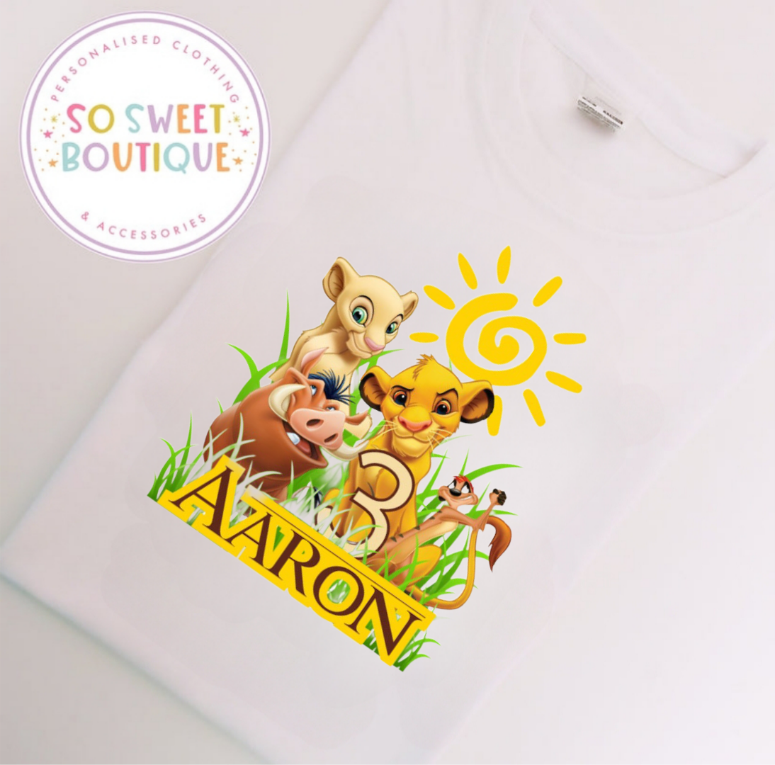 White T-shirt featuring The Lion King themed birthday design from SoSweetBoutiqueLtd, with colorful lion and party elements.