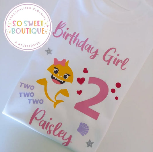 Baby Shark themed white birthday T-shirt for toddlers, featuring colorful shark graphics and playful design by SoSweetBoutiqueLtd.