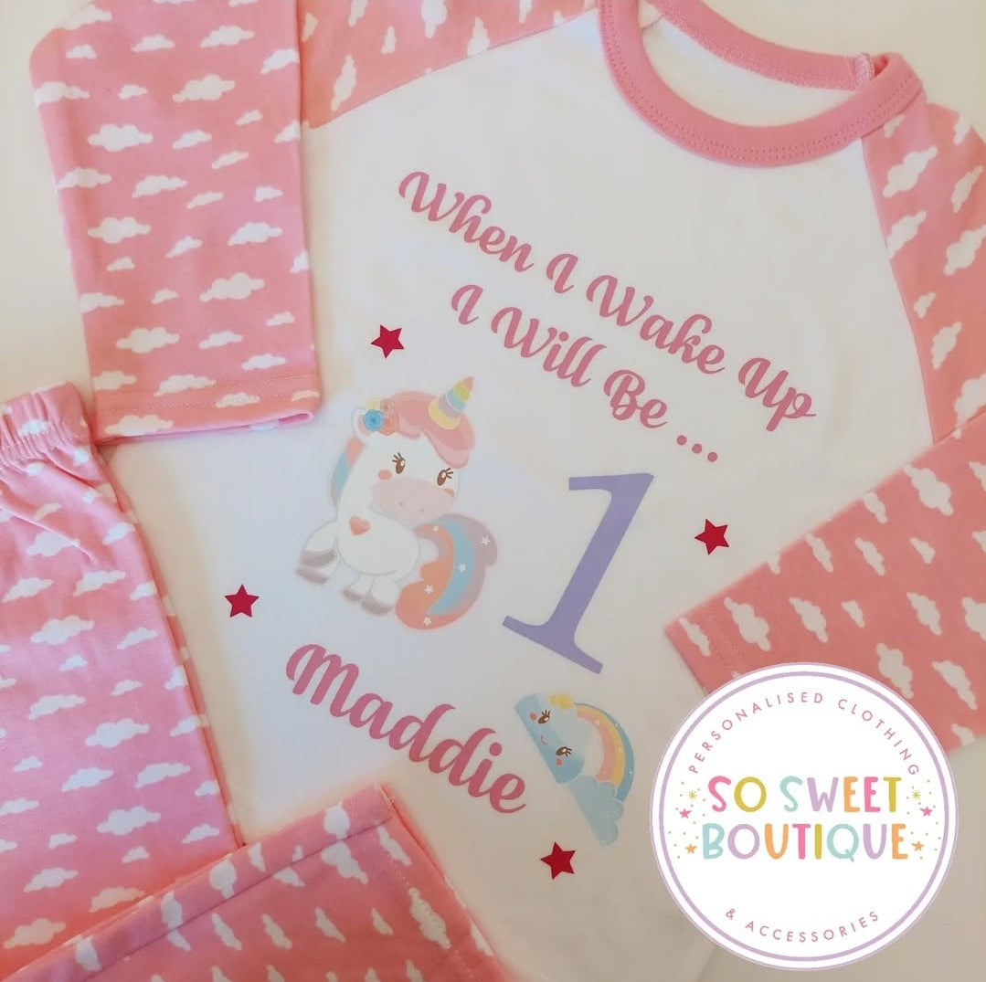 Pink and white personalized unicorn birthday pajamas for babies, featuring soft fabric and a cute unicorn design by SoSweetBoutiqueLtd.
