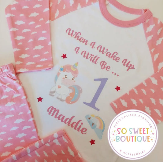 Pink and white personalized unicorn birthday pajamas for babies, featuring soft fabric and a cute unicorn design by SoSweetBoutiqueLtd.